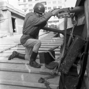 Brigadiano uniformizado de capacete, agachado com uma arma, a posto, no terraço do Palácio Piratini. 