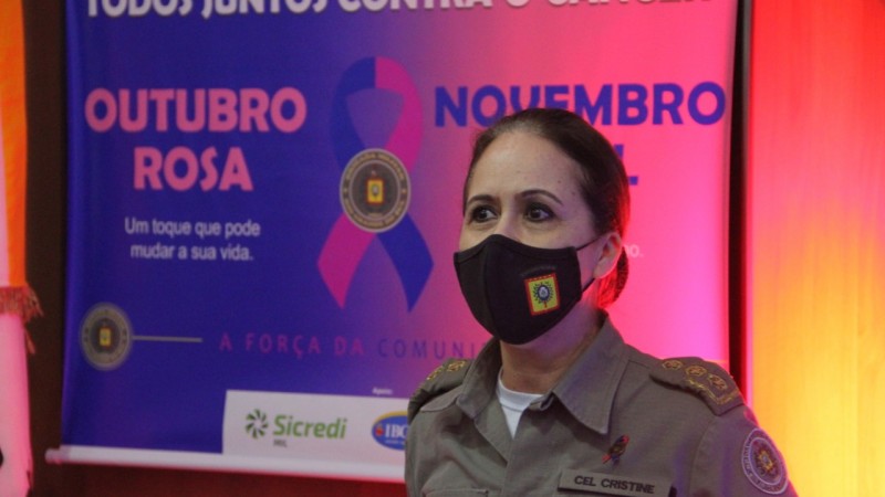 Coronel Cristine Rasbold em evento na Brigada Militar, ao fundo um banner alusivo ao Outubro Rosa e Novembro Azul