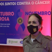 Coronel Cristine Rasbold em evento na Brigada Militar, ao fundo um banner alusivo ao Outubro Rosa e Novembro Azul