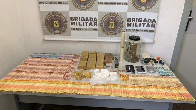 A imagem mostra a droga e o dinheiro, entre outros objetos j&aacute; mencionados no texto sobre uma mesa
