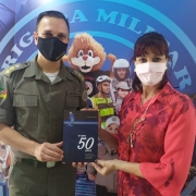 Autora entregando livro ao Chefe da Comunicação Social da BM, Tenente-Coronel Cilon