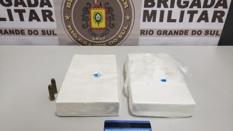 A imagem mostra dos tijolos de coca&iacute;na e duas muni&ccedil;&otilde;es sobre uma mesa