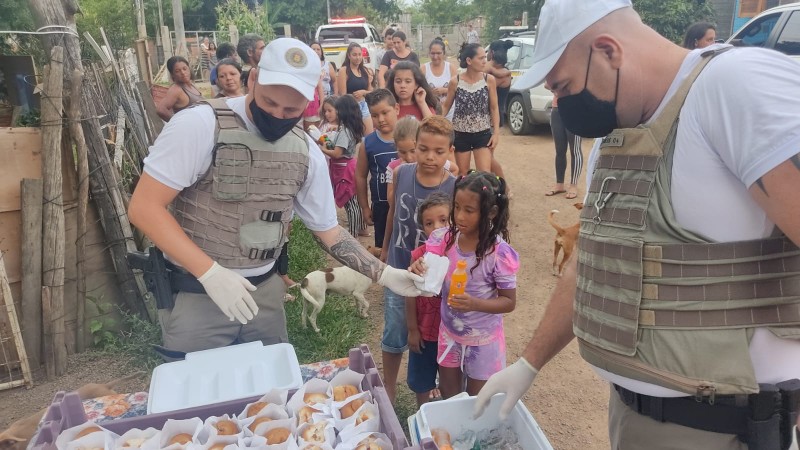 Policial militar entregando cachorro quente para criança