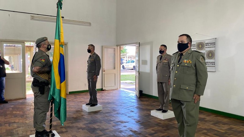 O comandante regional ao meio e ao lado os comandantes substituto e substituido, a frente da bandeira nacional brasileira.