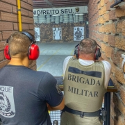 Policial militar atirando alvo e instrutor ao lado