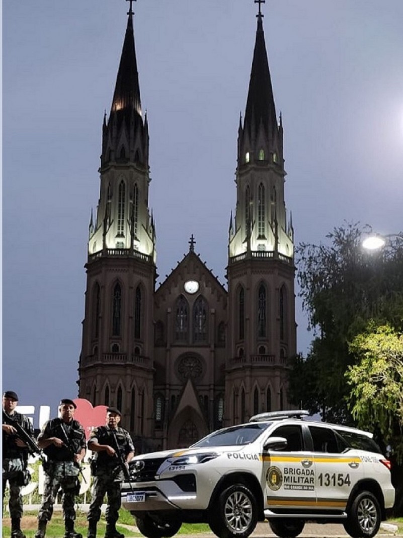Viatura policial militar ao lado três policiais e ao fundo a catedral do centro de Santa Cruz do Sul/RS