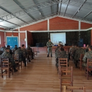 Policial em pé e militares EB sentados