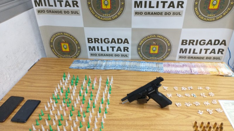 Material apreendido exposto em uma mesa, drogas, arma e munições, além de outras apreensões.