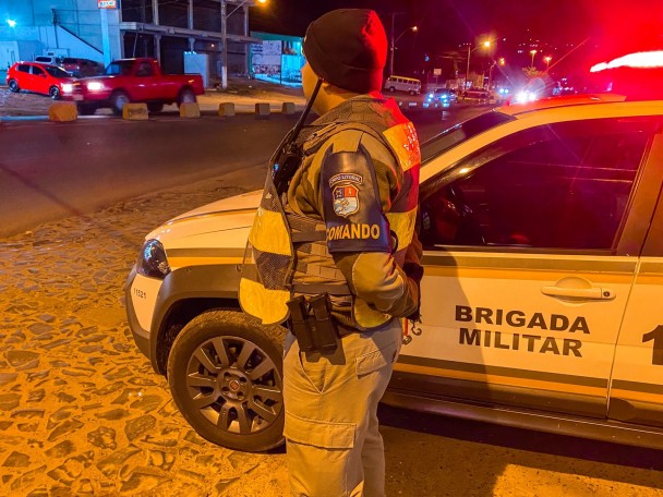 PM ao lado de viatura em local de visibilidade para segurança nas ruas