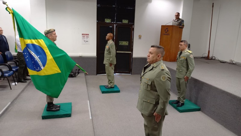 Imagem mostra coronéis perfilados dentro de um auditório durante a solenidade