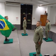 Imagem mostra coronéis perfilados dentro de um auditório durante a solenidade