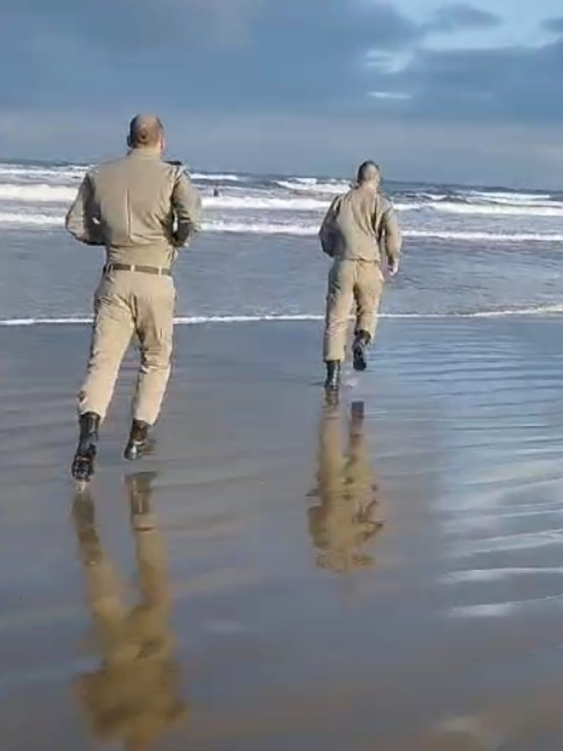 Policiais militares correm em dire&ccedil;&atilde;o ao mar para efetuar o salvamento de um homem que se afogava 