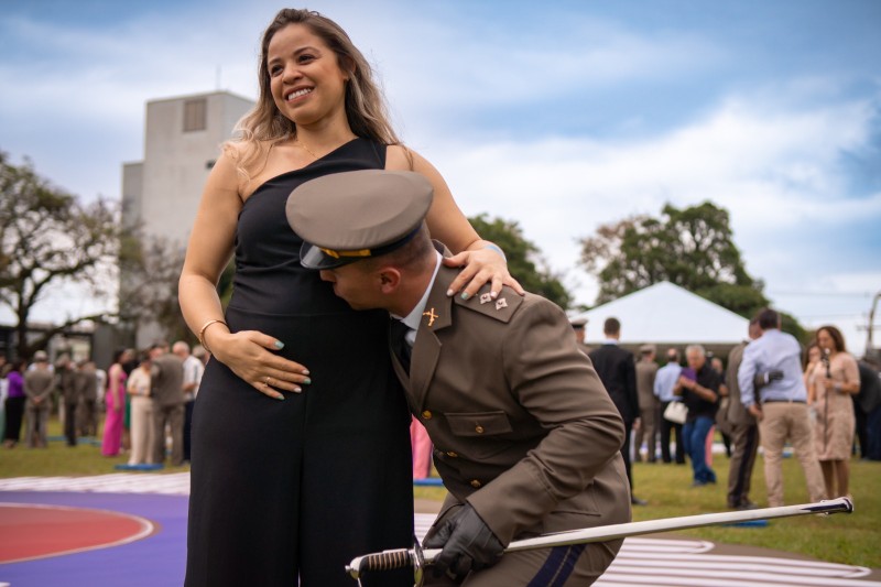 Formando comemora beijando a barriga de sua mulhar, grávida.