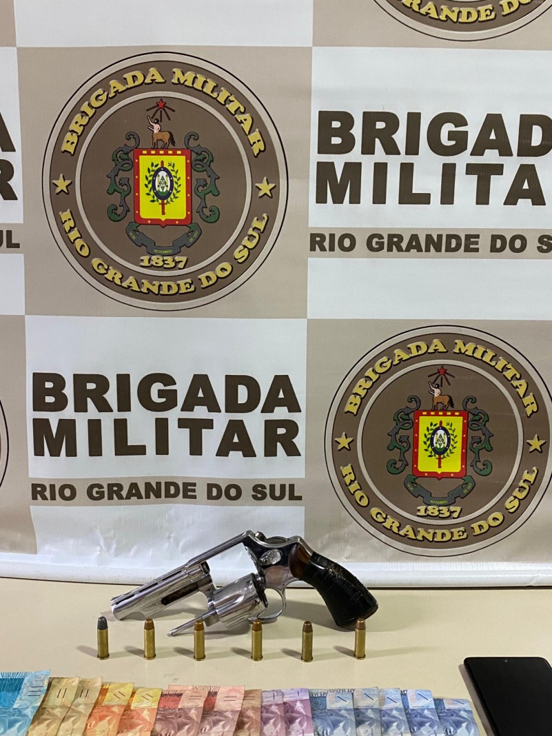 Na imagem há um revólver calibre .38, seis munições intactas, um aparelho celular e um valor em dinheiro 