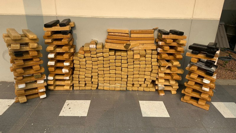 Imagem apresenta grande volume de drogas em frente a uma parede cinza com branca 