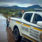 Imagem mostra camionete da BM conduzindo um barco em uma via alagada e seguindo para efetuar o resgate de vítimas