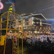 &Aacute; noite, durante um show na &aacute;rea central de Gramado, a rua est&aacute; ocupada pelo p&uacute;blico presente sentado e um PM est&aacute; sobre um pedestal, equipamento que possibilita uma visualiza&ccedil;&atilde;o panor&acirc;mica. 