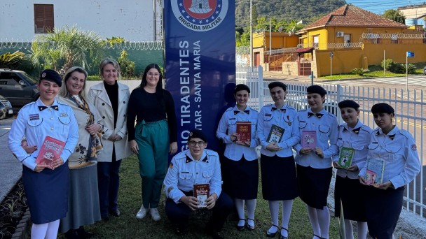 Estudantes e servidores em fileira posam para a foto em frente ao CT em dia ensolarado. 