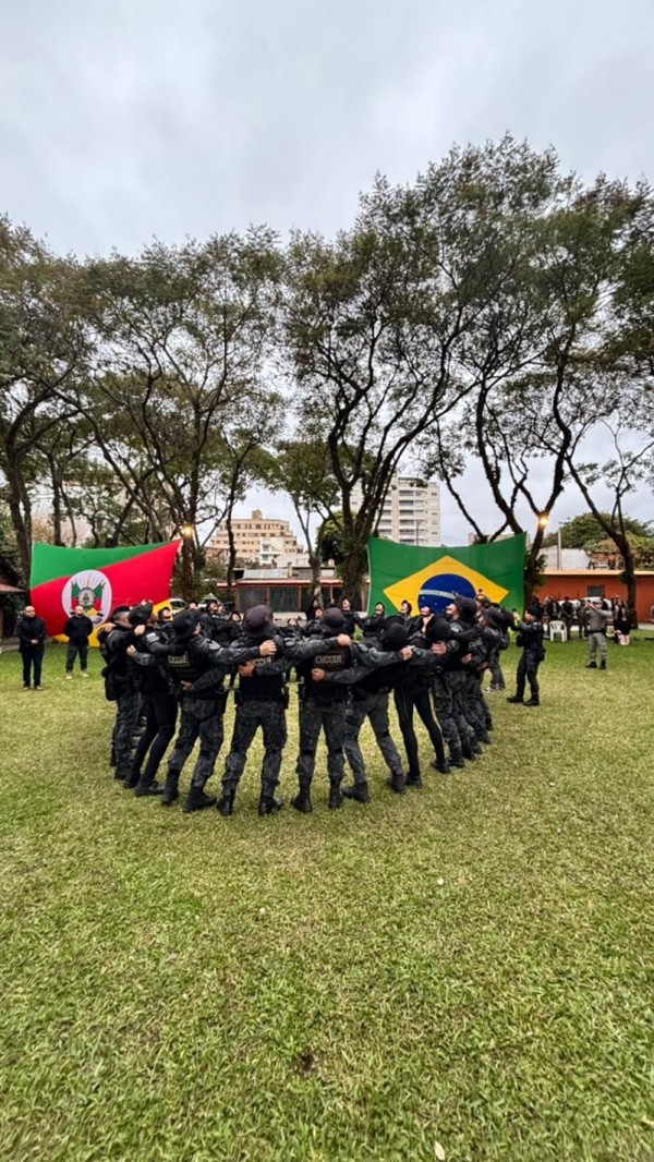 Foto mostra policiais reunidos em formato circular em frente em campo aberto