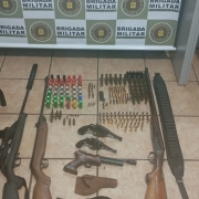 Apreens&otilde;es realizadas: muitas armas de fogo de cano longo dispostas, junto a muni&ccedil;&otilde;es, no ch&atilde;o.